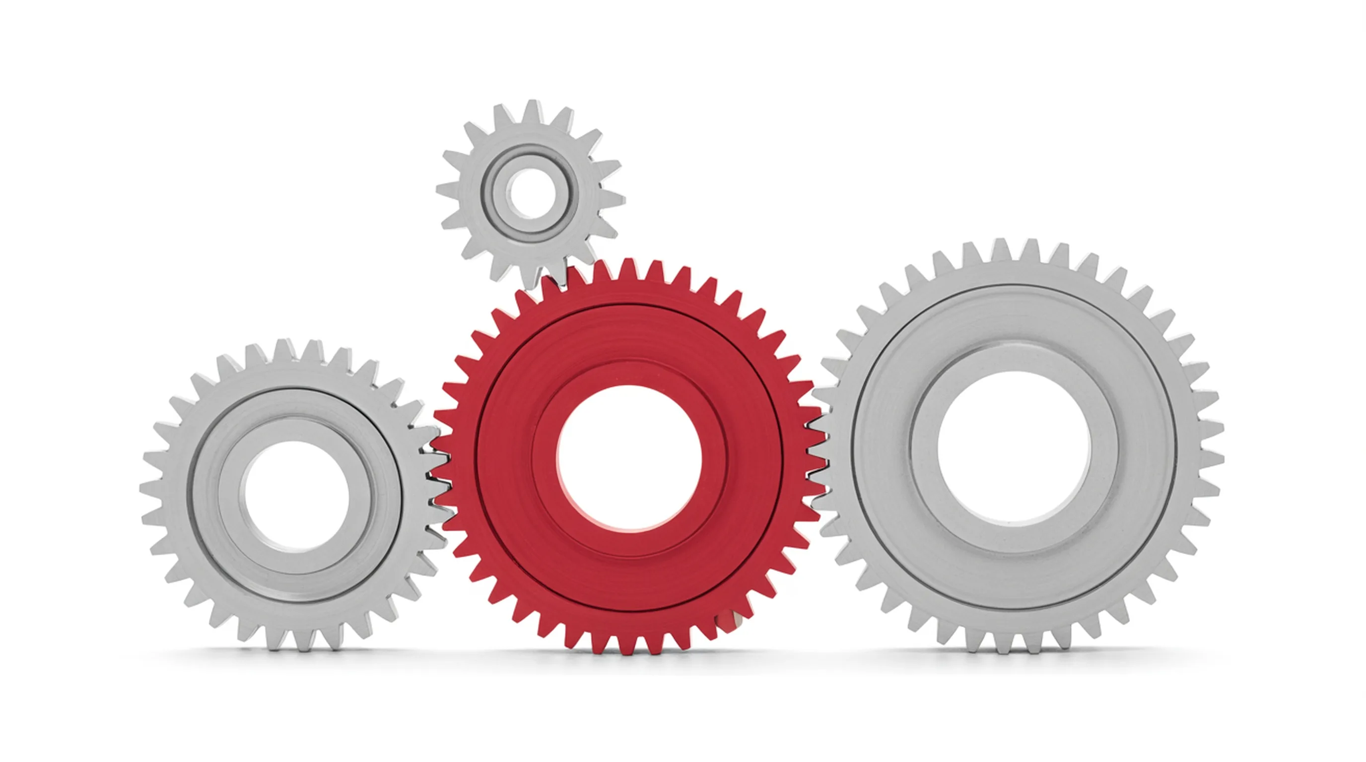 Three machined gears of different sizes meshed together, the centre gear anodised red against the others in light grey.