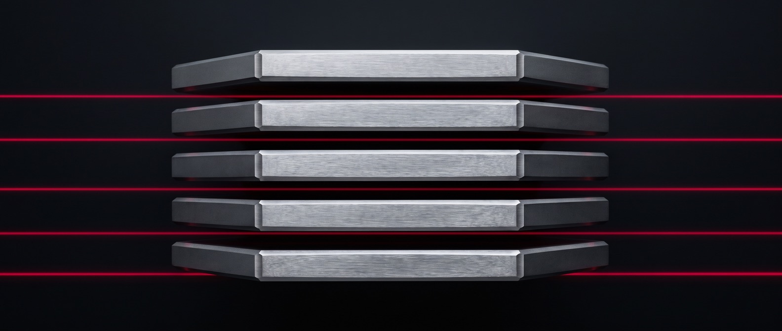 Five machined steel plates held apart in an exploded stack, with a thin red light line running through each gap.