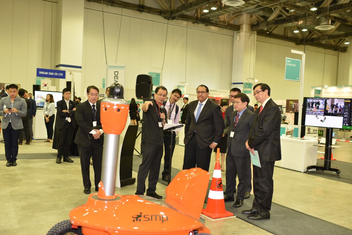 The surveillance robot surrounded by guests and delegates on the expo floor at its premiere.