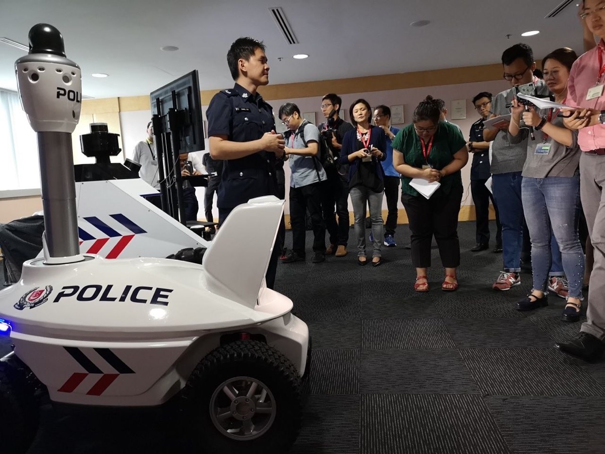 A Singapore Police Force officer briefing television press on the S5 robot's patrol technology at the Police Workplan Seminar 2018.