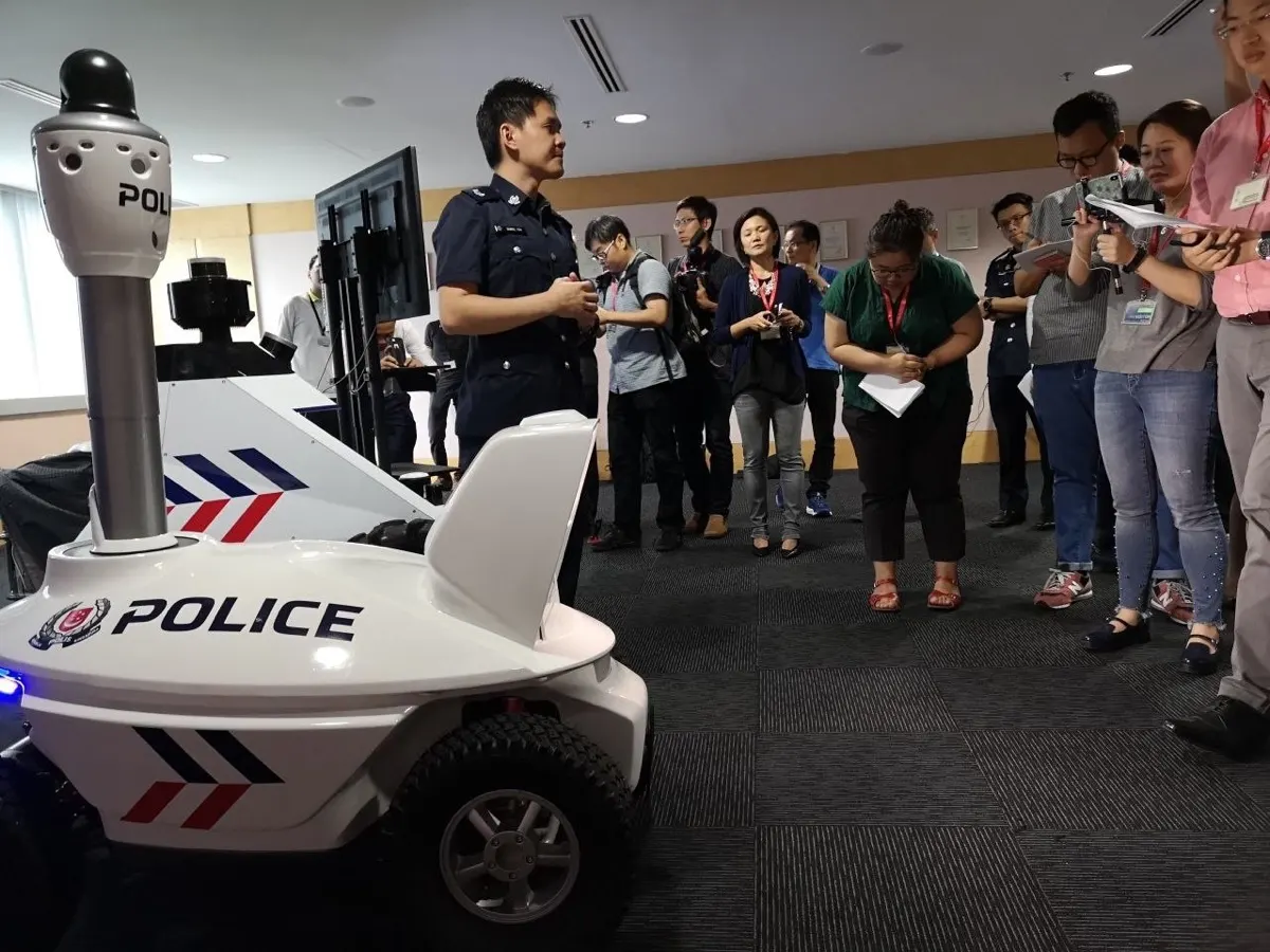 A Singapore Police Force officer briefing television press on the S5 robot's patrol technology at the Police Workplan Seminar 2018.