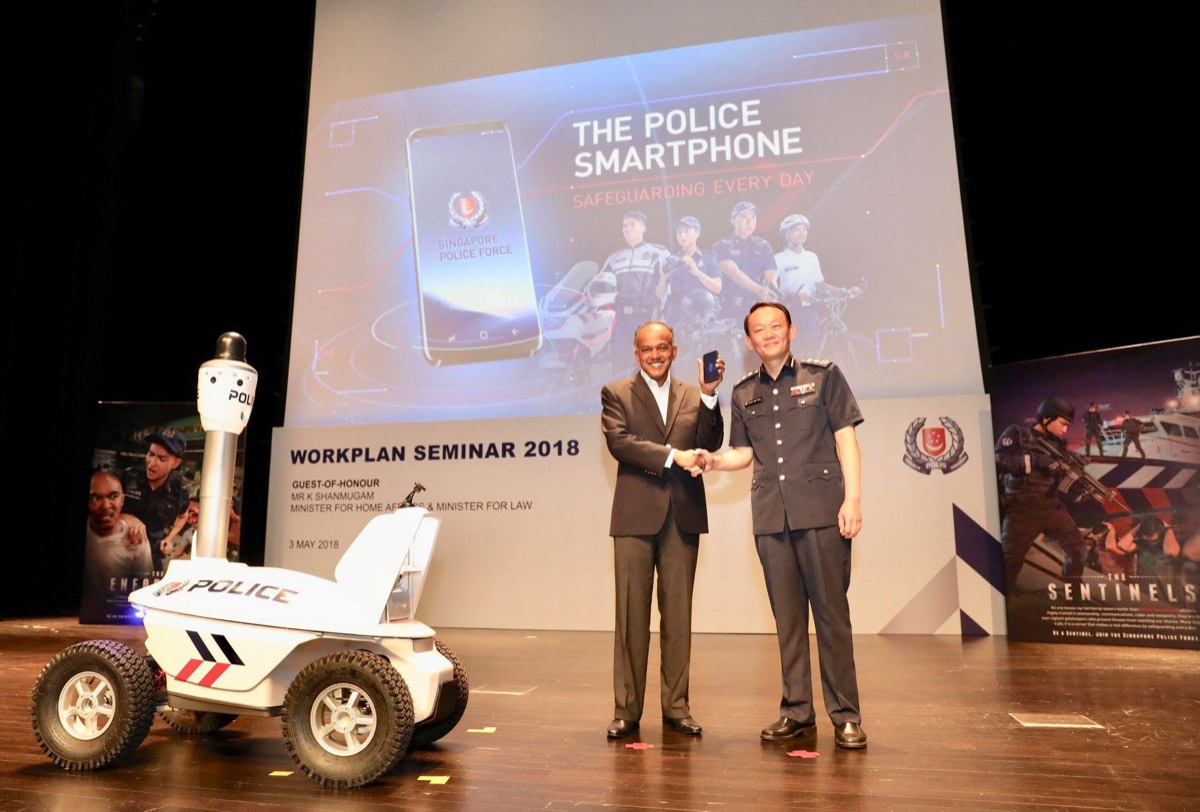 The S5 patrol robot on stage at the Workplan Seminar, beside a presentation slide on the police smartphone.